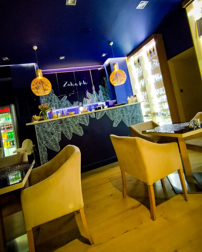 Sala z żółtymi fotelami i barem pod wiklinowymi lampami